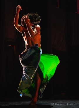 Male African-American dancer in motion, bare chested with green toga like skirt
