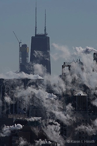 Steam from chimneys throw blanket of smoke over the Hancock building and downtown Chicago.