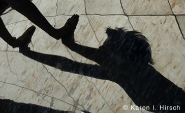Silhouette and reflection of woman reaching out at the Bean sculpture in Chicago