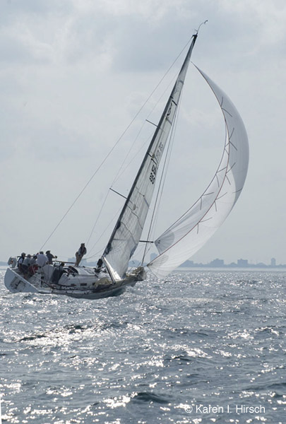 Sailboat with white spinnaker on sparkling water